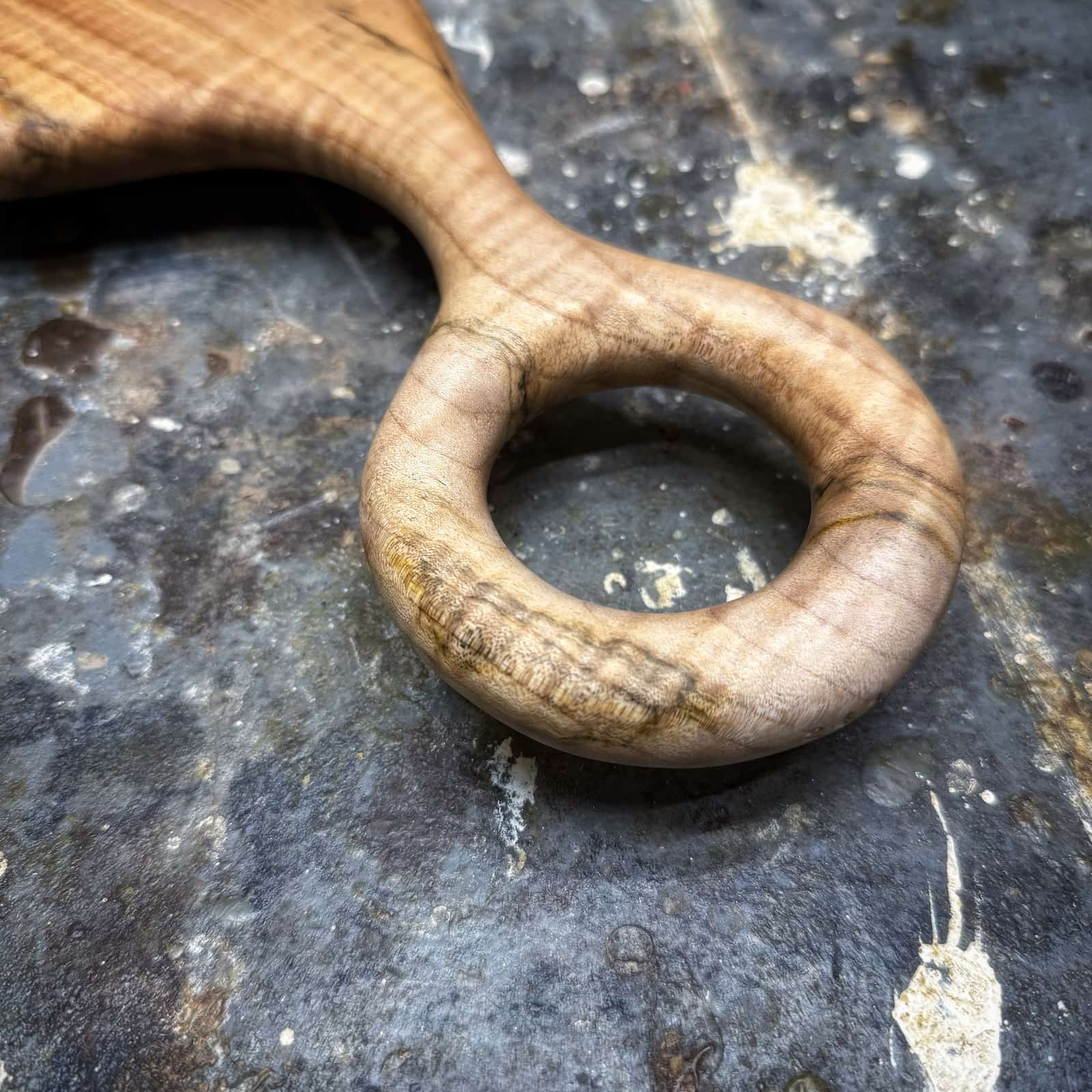 close-up of smooth carved ring handle on ambrosia maple board