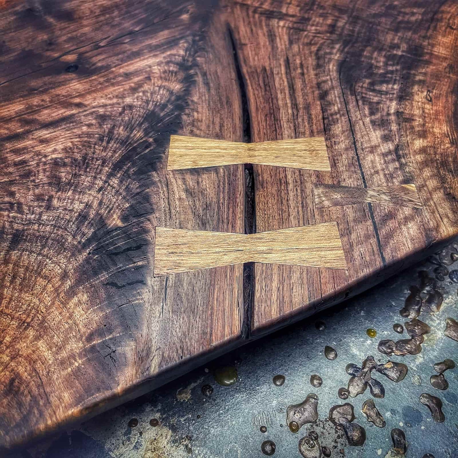 installed hardwood joinery accents set into a rich dark surface showing clean geometry, tight fitting work, and refined craftsmanship by JML Woodcraft