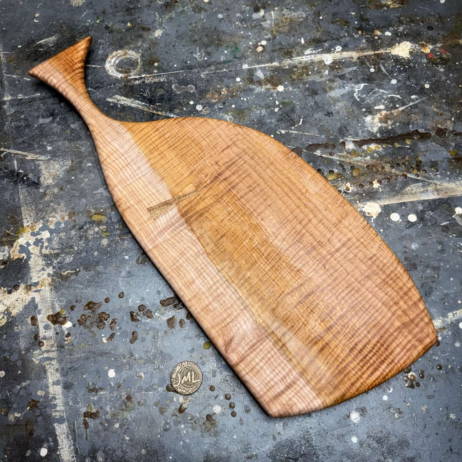 curly two tone maple serving board with sculpted tapered handle and decorative maple inlay