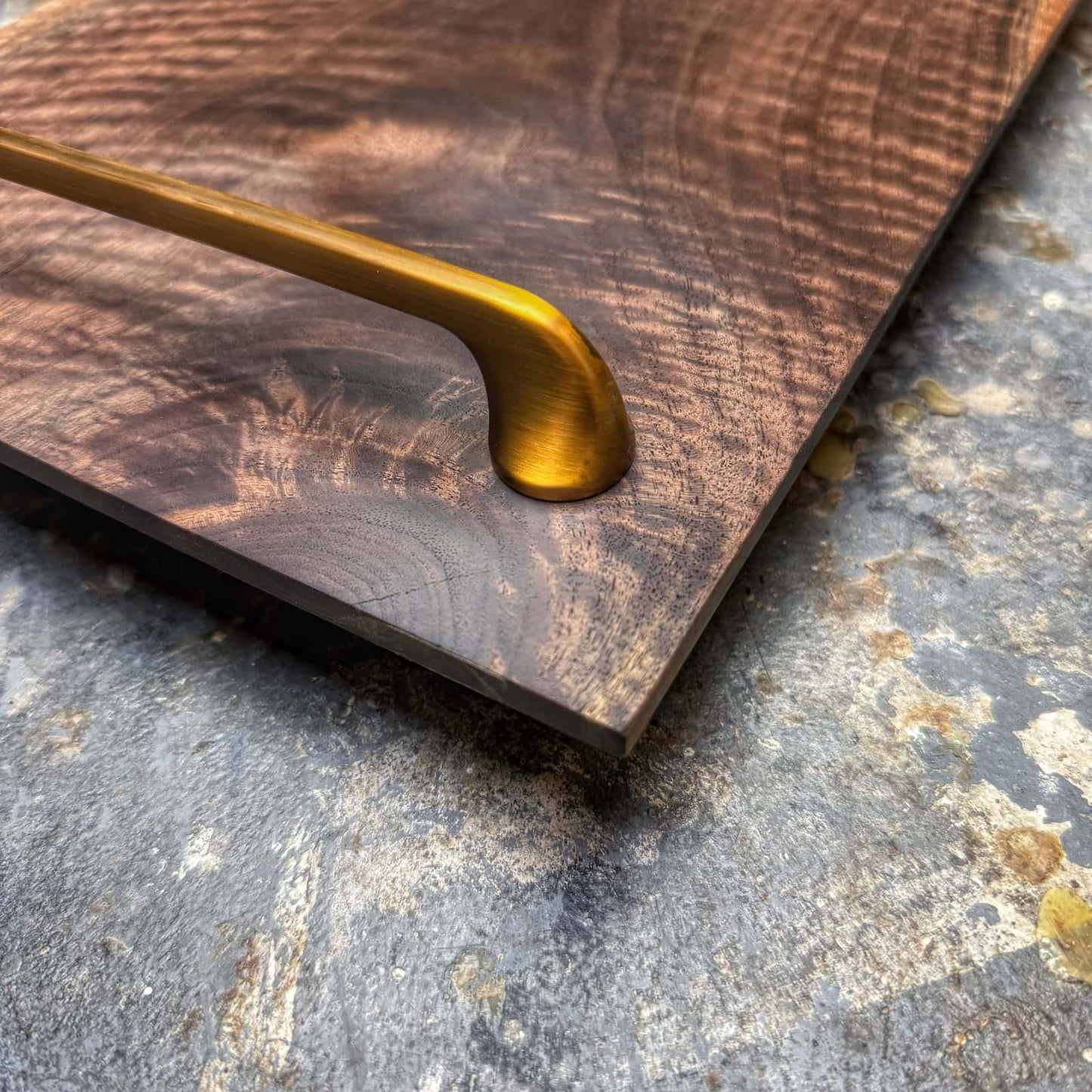closeup of brushed gold handle and walnut surface detail