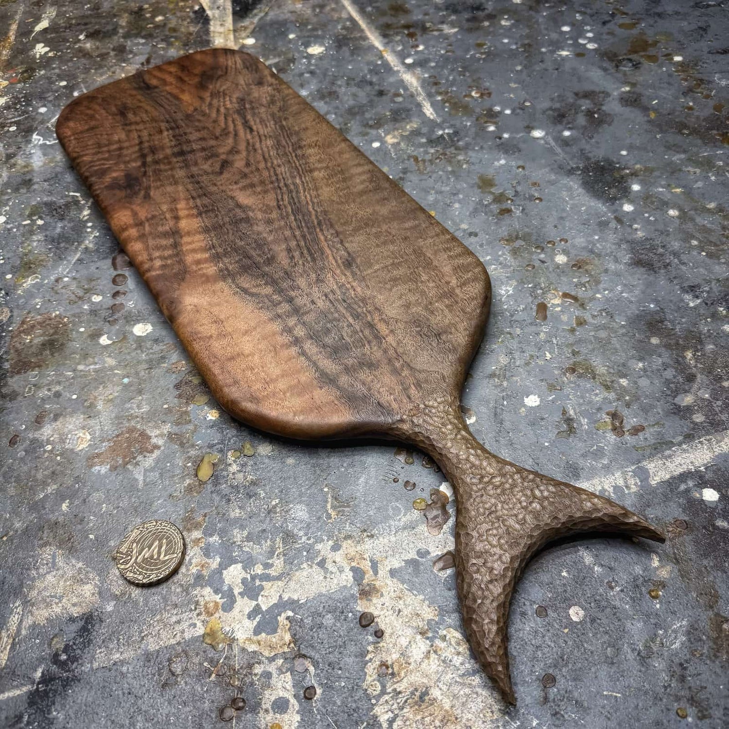 english walnut serving board with textured fish tail handle on workshop surface