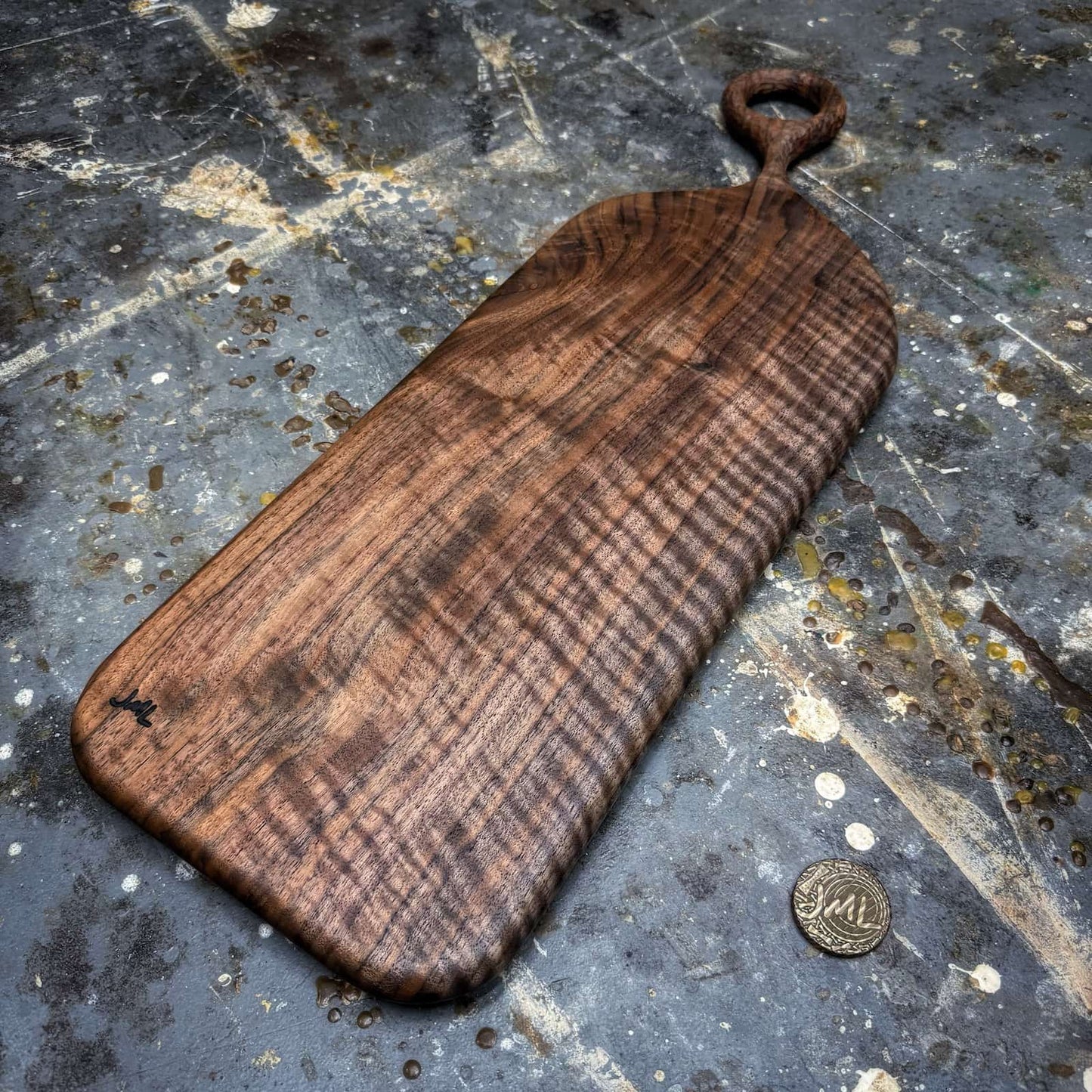 figured black walnut serving board featuring carved handle detail