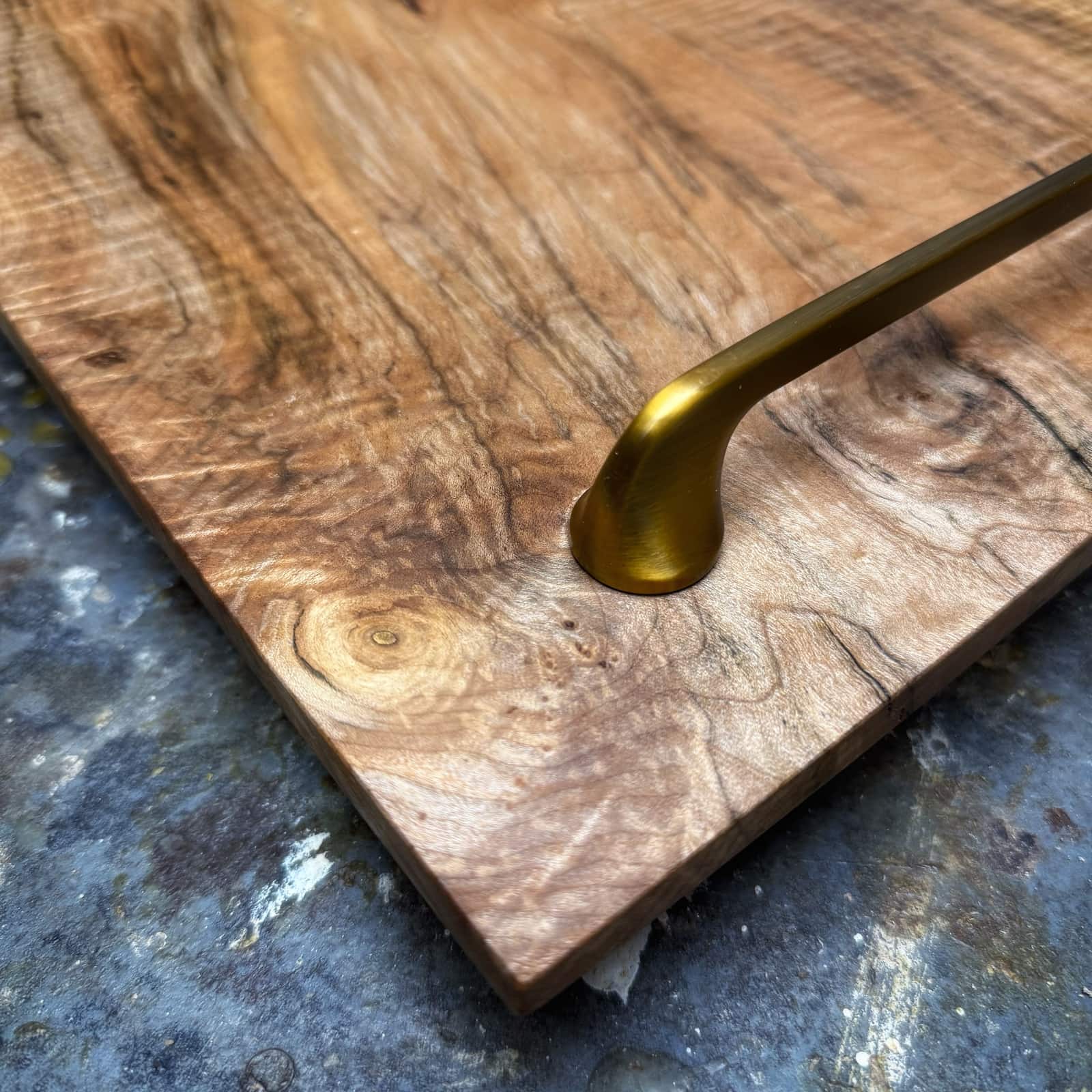 Detail view of gold handle mounted on figured curly maple tray