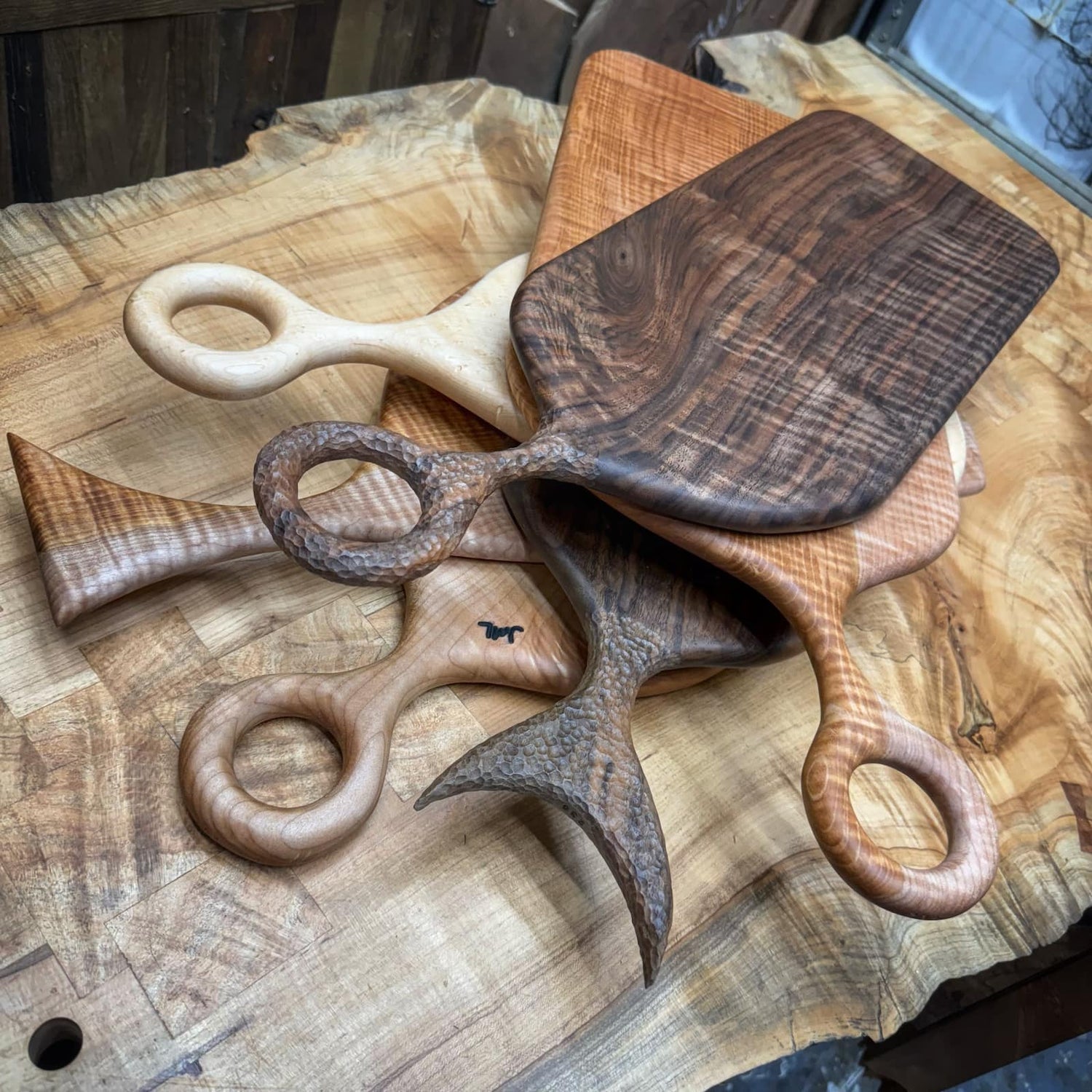 stack of handcrafted serving boards made from figured hardwoods with sculpted and textured handles