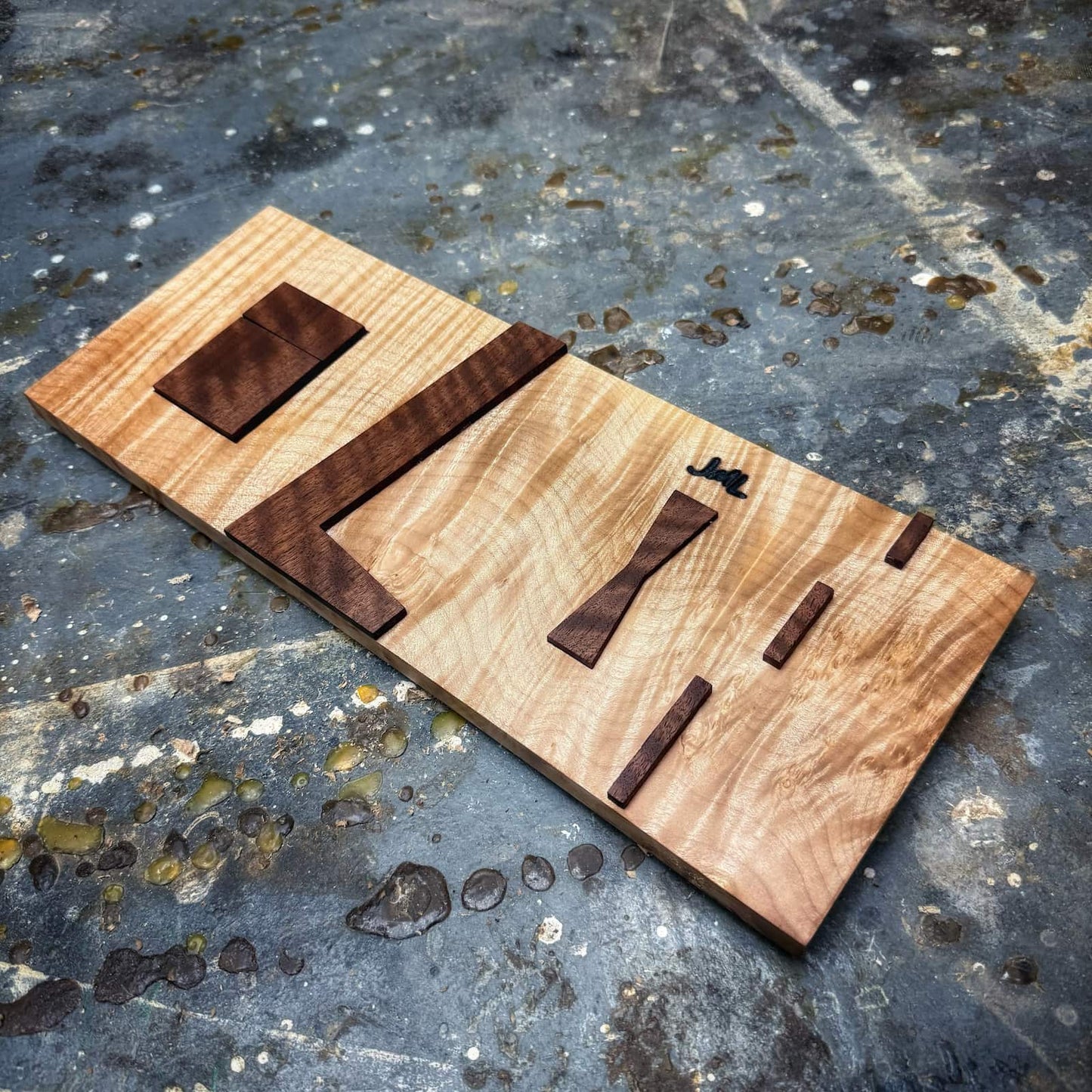 Curly maple base inlay jig with curly walnut top parts on shop floor
