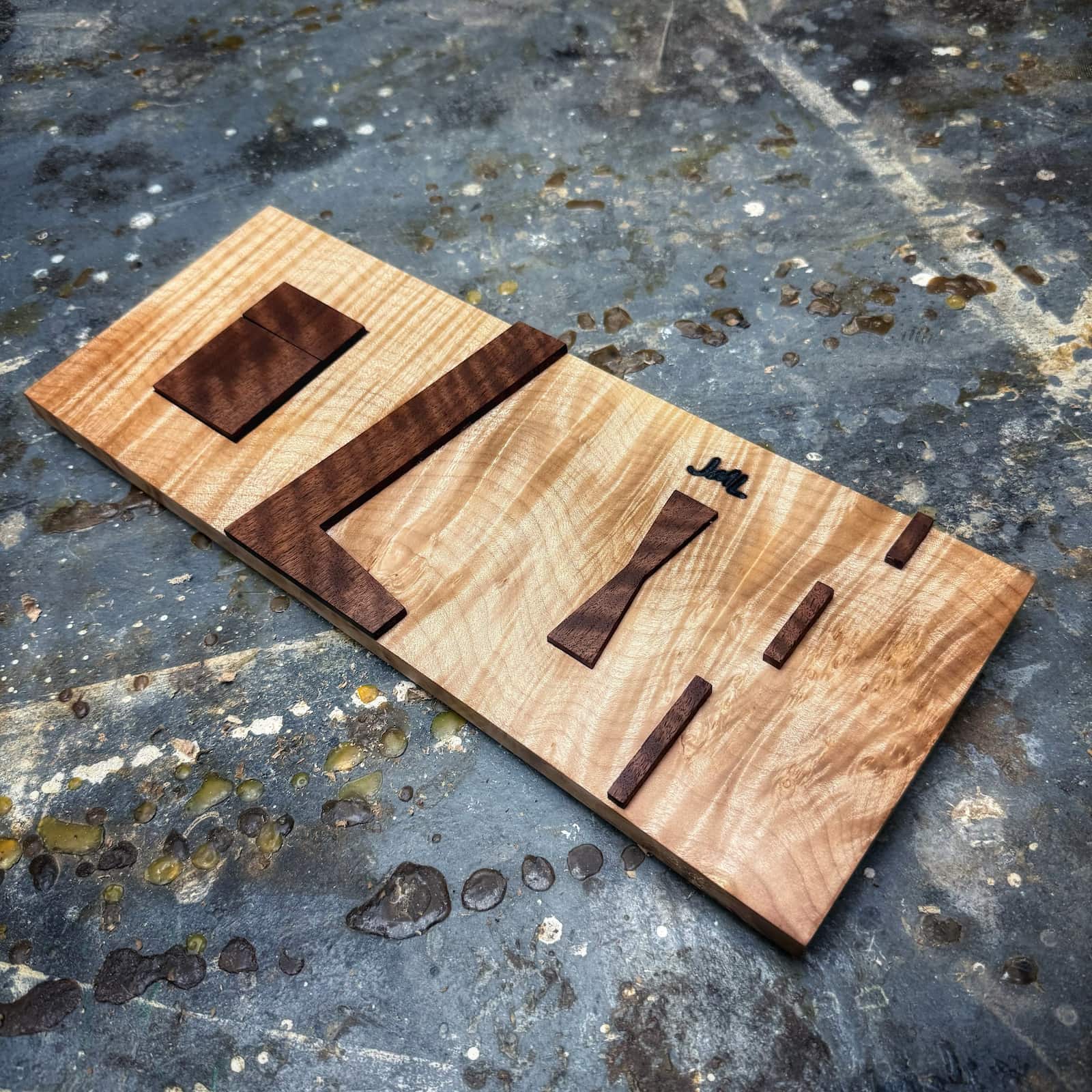 Curly maple base inlay jig with curly walnut top parts on shop floor