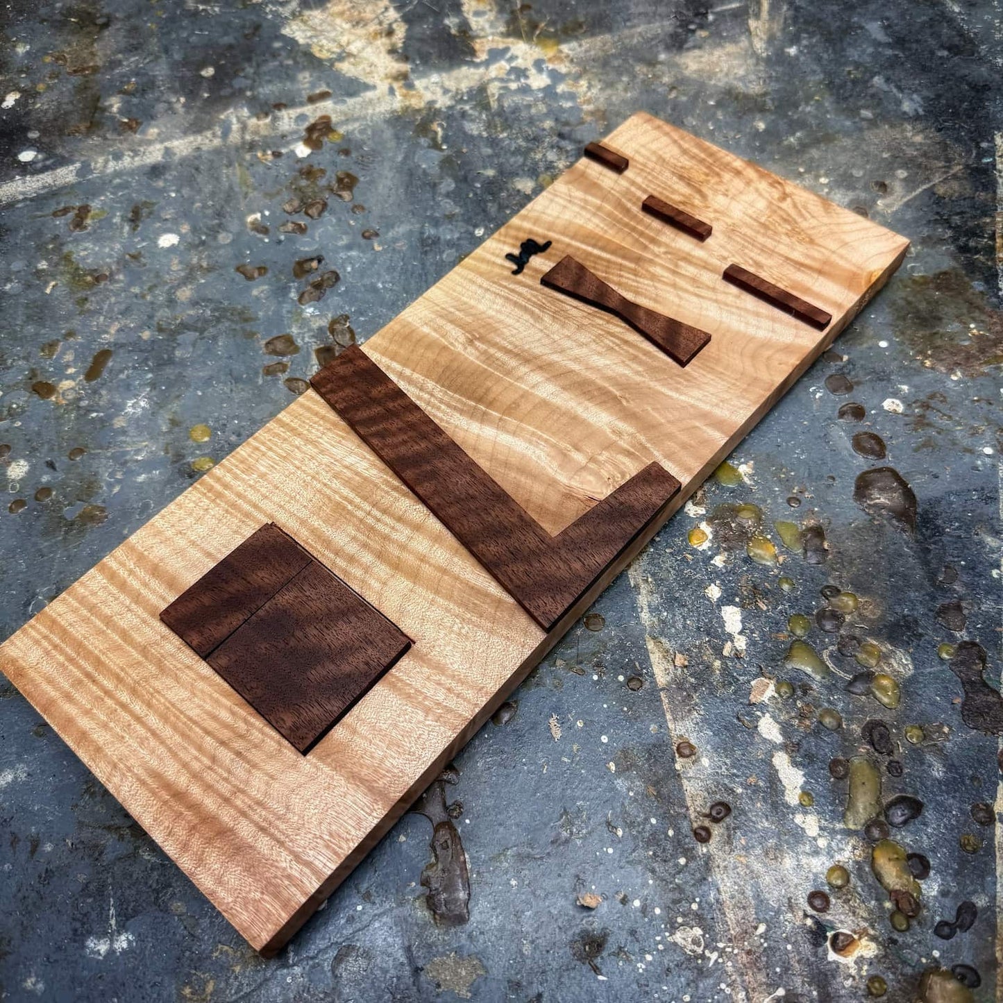 Detail view of curly walnut inlay jig components on curly maple base