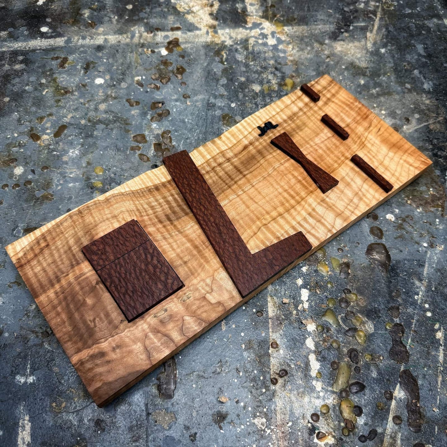Close-up of leopardwood inlay shapes on curly maple jig base