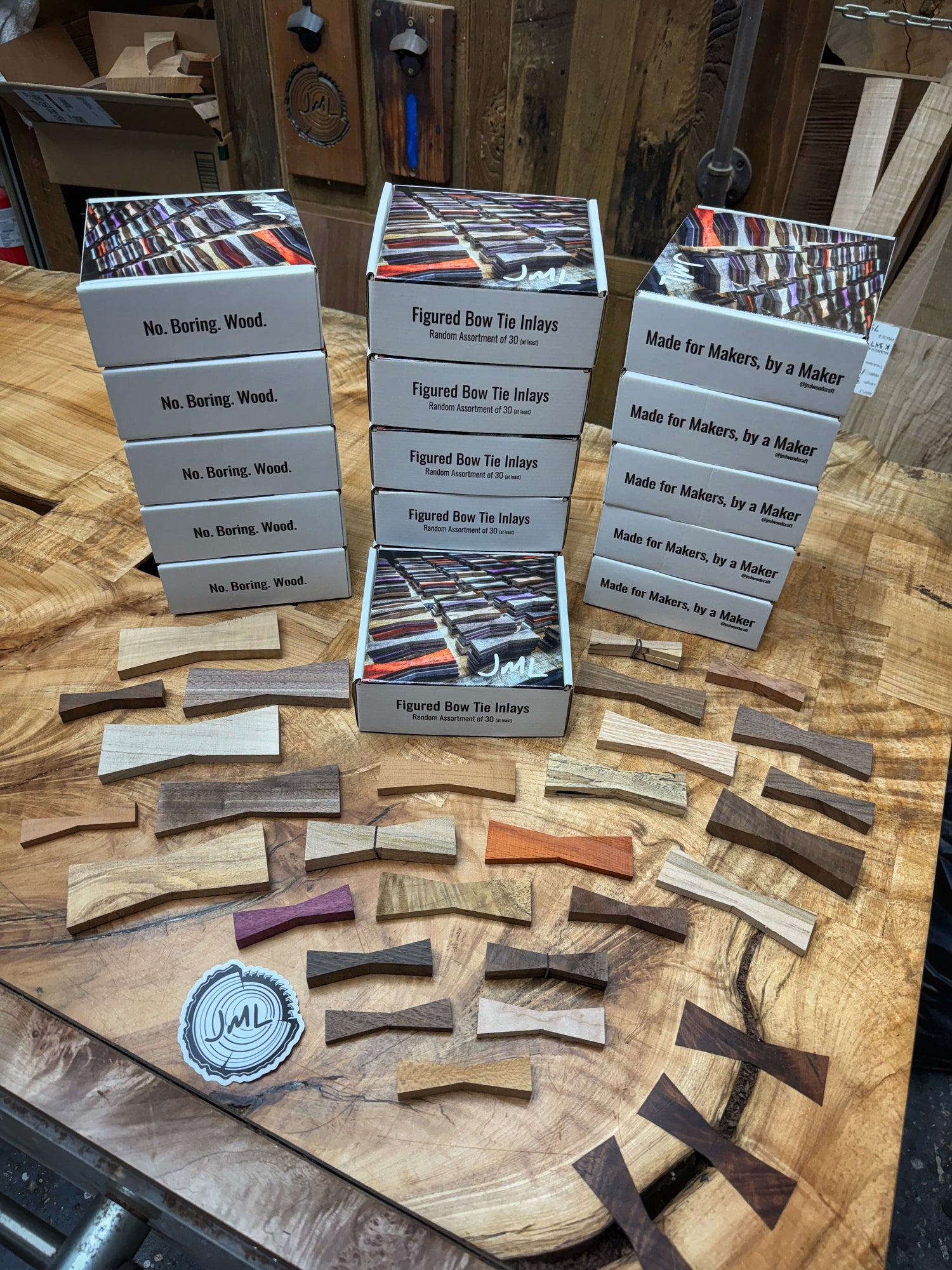 Open box of handcrafted bow tie inlays on a workbench showing assorted hardwood pieces