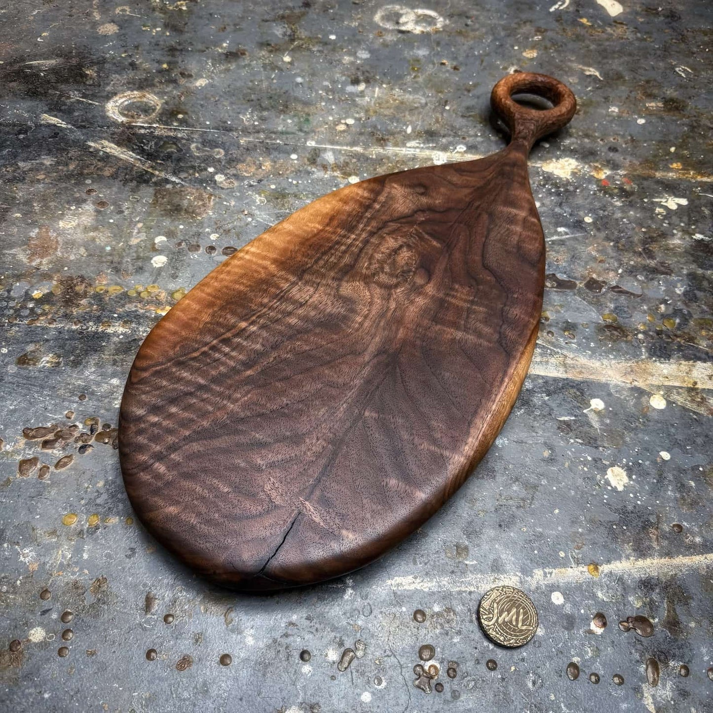 sculpted walnut serving board featuring textured ring handle