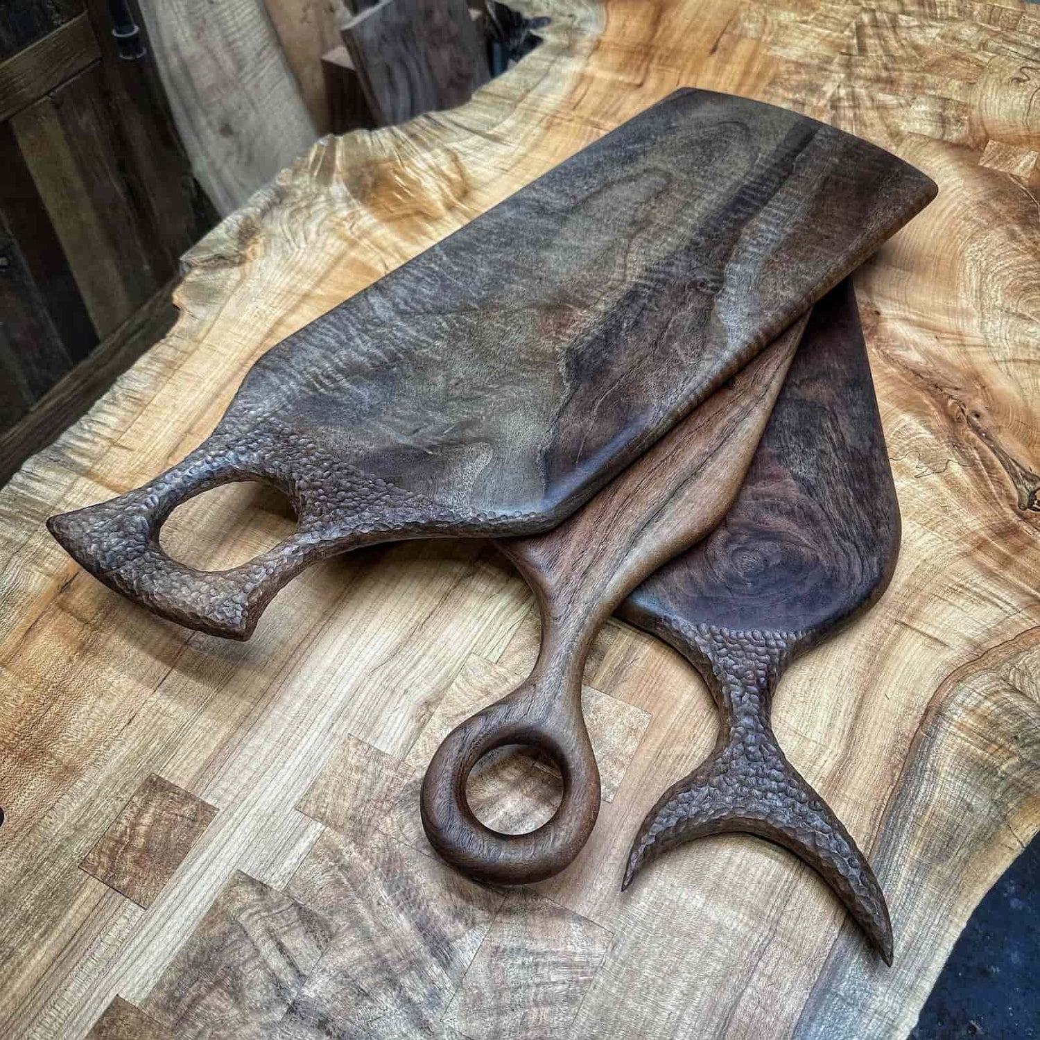 collection of handcrafted hardwood serving boards arranged on a workshop surface highlighting varied figure, warm tones, and refined shaping by JML Woodcraft