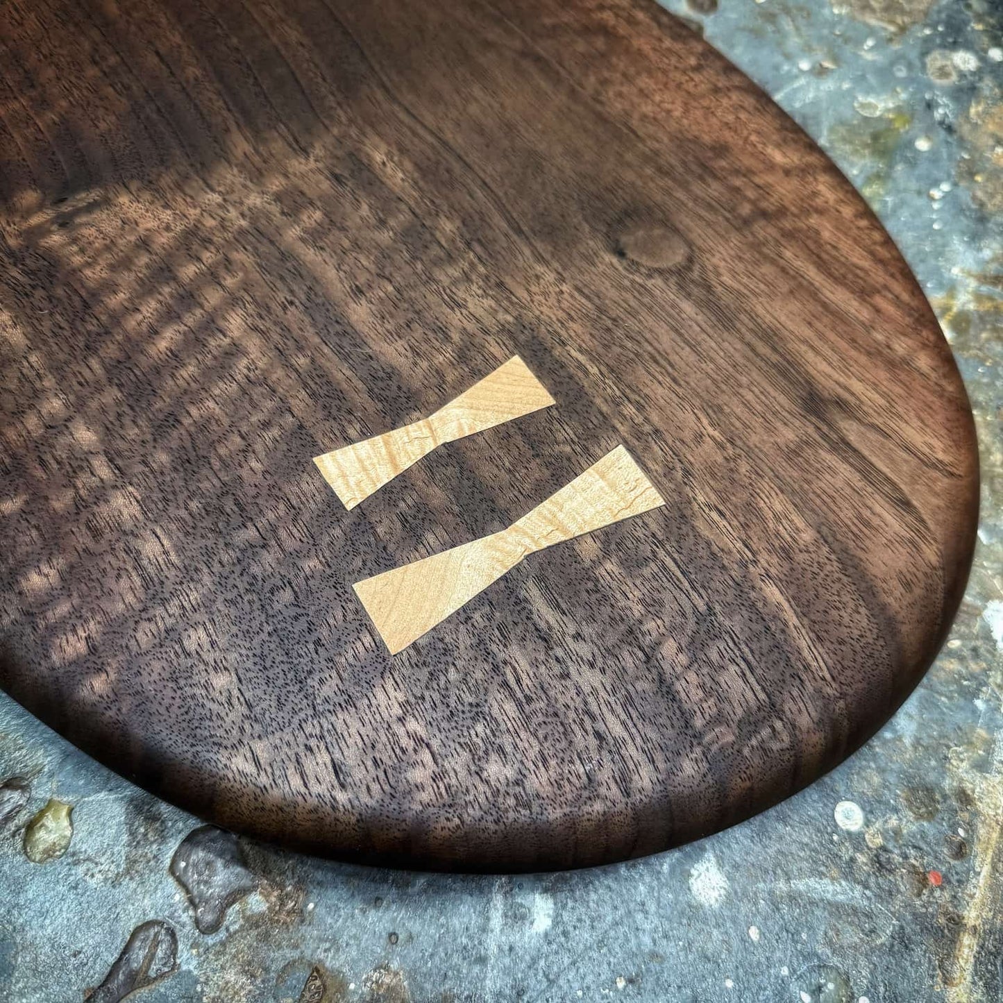 close-up of book-matched curly maple inlays set into walnut board