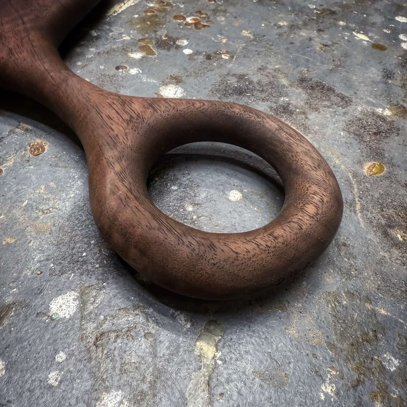 close-up of smooth carved round handle on walnut serving board